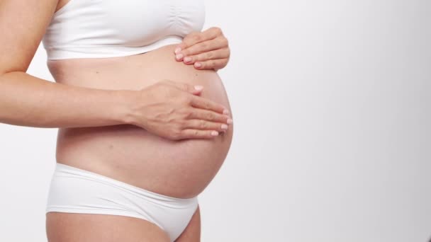 Mujer embarazada joven, feliz y saludable sobre fondo blanco. Vídeo del estudio. Esperanza del bebé, embarazo y concepto de maternidad. — Vídeo de stock