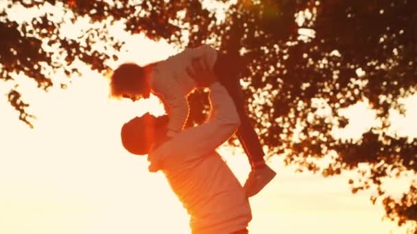 Liefdevolle familie wandelingen op het platteland tijdens zonsondergang. Vader speelt met zijn dochter. Het concept van liefde, ouderlijke zorg en kinderen. — Stockvideo