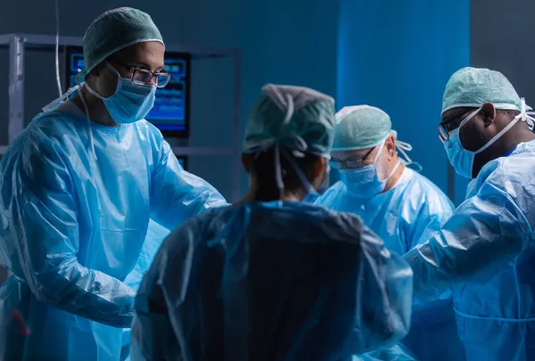 Multiracial team of professional medical surgeons performs the surgical operation in a modern hospital. Doctors are working to save the patient. Medicine, health, cardiology and transplantation. — Stock Photo, Image