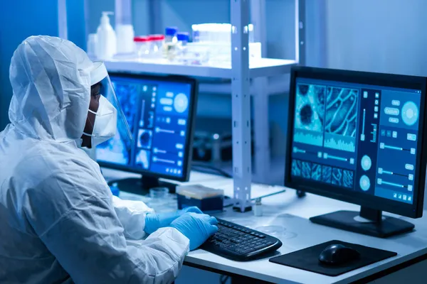 Afrikalı-Amerikalı bilim adamı laboratuvar ekipmanları, mikroskop ve bilgisayar teknolojisi kullanarak bir laboratuarda çalışıyor. Yeni ilaçların ve aşıların icadı. Bilim ve Sağlık kavramı.