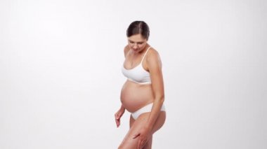 Genç, mutlu ve sağlıklı hamile bir kadın beyaz arka planda. Stüdyo videosu. Bebek beklentisi, hamilelik ve annelik kavramı.