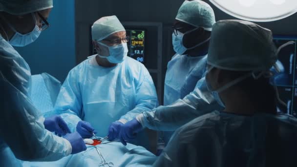 El equipo multirracial de cirujanos médicos profesionales realiza la operación quirúrgica en un hospital moderno. Los médicos están trabajando para salvar al paciente. Medicina, salud, cardiología y trasplante. — Vídeos de Stock