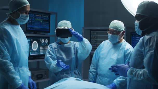 Equipe multirracial de cirurgiões médicos profissionais realiza a operação cirúrgica em um hospital moderno usando tecnologia de realidade virtual. Conceito de medicina, saúde e neurocirurgia. — Vídeo de Stock