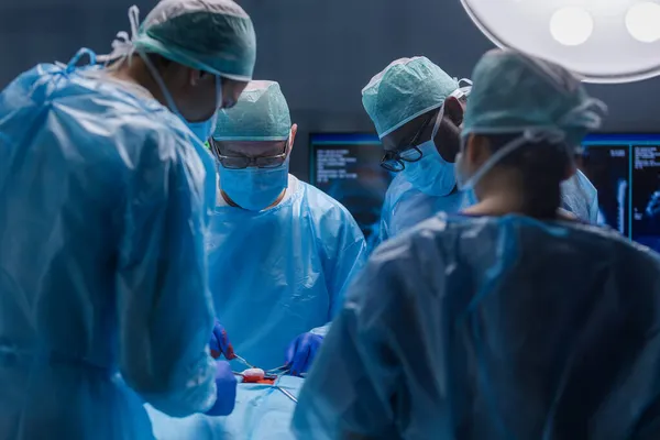 Equipe multirracial de cirurgiões médicos profissionais realiza a operação cirúrgica em um hospital moderno. Os médicos estão a trabalhar para salvar o paciente. Medicina, saúde, cardiologia e transplante. — Fotografia de Stock