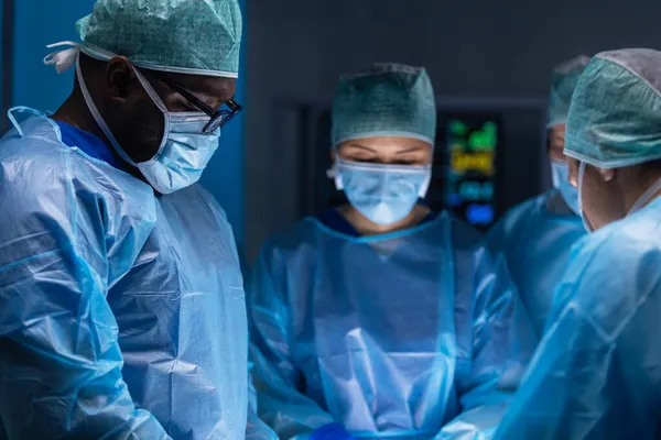 Professzionális orvosi sebészek multiracionális csapata végzi a műtétet egy modern kórházban. Az orvosok azon dolgoznak, hogy megmentsék a beteget. Gyógyászat, egészségügy, kardiológia és transzplantáció. Jogdíjmentes Stock Fotók