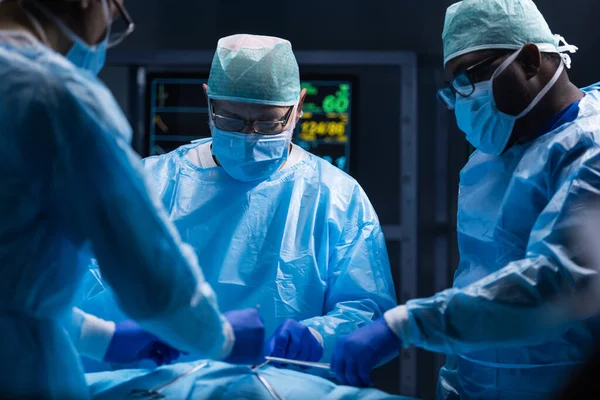 El equipo multirracial de cirujanos médicos profesionales realiza la operación quirúrgica en un hospital moderno. Los médicos están trabajando para salvar al paciente. Medicina, salud, cardiología y trasplante. — Foto de Stock