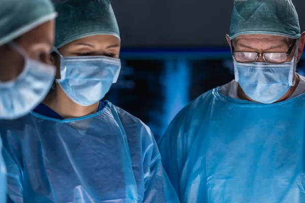 El equipo multirracial de cirujanos médicos profesionales realiza la operación quirúrgica en un hospital moderno. Los médicos están trabajando para salvar al paciente. Medicina, salud, cardiología y trasplante. — Foto de Stock