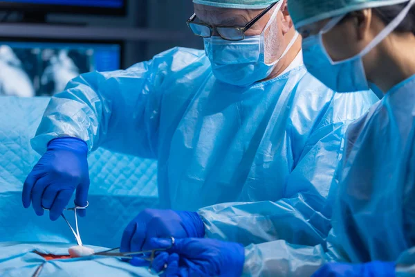 Multiracial team of professional medical surgeons performs the surgical operation in a modern hospital. Doctors are working to save the patient. Medicine, health, cardiology and transplantation. — Stock Photo, Image