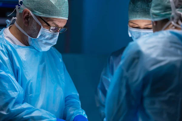 Multiracial team of professional medical surgeons performs the surgical operation in a modern hospital. Doctors are working to save the patient. Medicine, health, cardiology and transplantation. — Stock Photo, Image