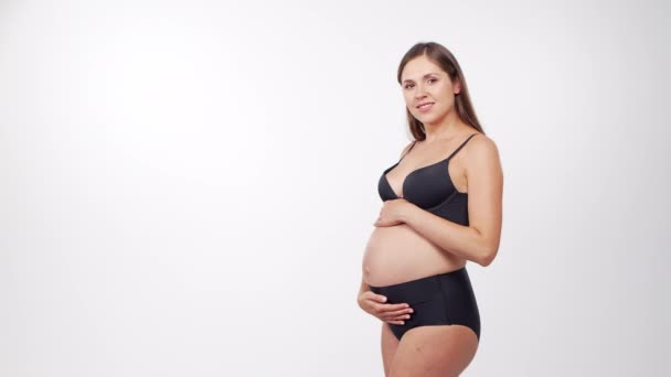 Young, happy and healthy pregnant woman on white background. Studio video. Baby expectation, pregnancy and motherhood concept. — Stock Video