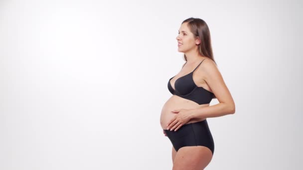 Mladá, šťastná a zdravá těhotná žena na bílém pozadí. Studio video. Dětské očekávání, těhotenství a mateřství koncept. — Stock video