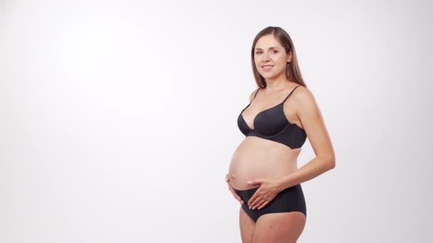 Ung, glad og sund gravid kvinde på hvid baggrund. Studie video. Baby forventning, graviditet og moderskab koncept. – Stock-video
