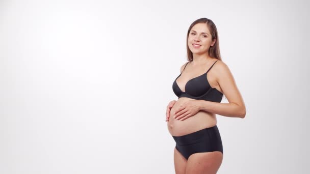 Genç, mutlu ve sağlıklı hamile bir kadın beyaz arka planda. Stüdyo videosu. Bebek beklentisi, hamilelik ve annelik kavramı. — Stok video
