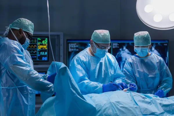 Equipe multirracial de cirurgiões médicos profissionais realiza a operação cirúrgica em um hospital moderno. Os médicos estão a trabalhar para salvar o paciente. Medicina, saúde, cardiologia e transplante. — Fotografia de Stock