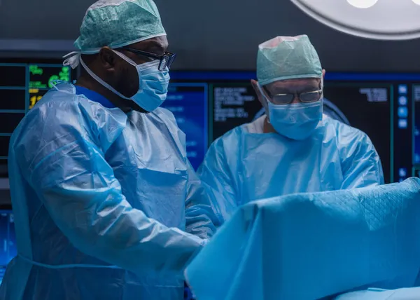 Wielorasowy zespół profesjonalnych lekarzy wykonuje operację chirurgiczną w nowoczesnym szpitalu. Lekarze pracują nad ratowaniem pacjenta. Medycyna, zdrowie i neurochirurgia. — Zdjęcie stockowe