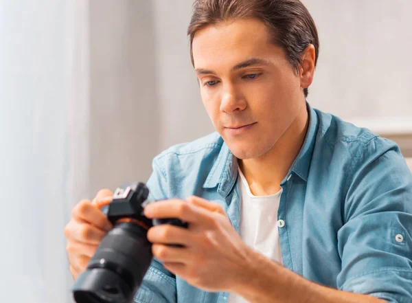 Fotografové na volné noze. Mladý muž s kamerou sedí u stolu a dívá se na fotky. Koncept vzdálené práce. — Stock fotografie