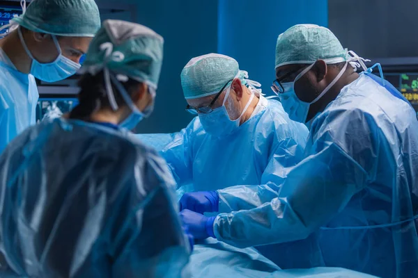 Ein multiethnisches Team professioneller Chirurgen führt den chirurgischen Eingriff in einem modernen Krankenhaus durch. Ärzte arbeiten daran, den Patienten zu retten. Medizin, Gesundheit, Kardiologie und Transplantation. — Stockfoto