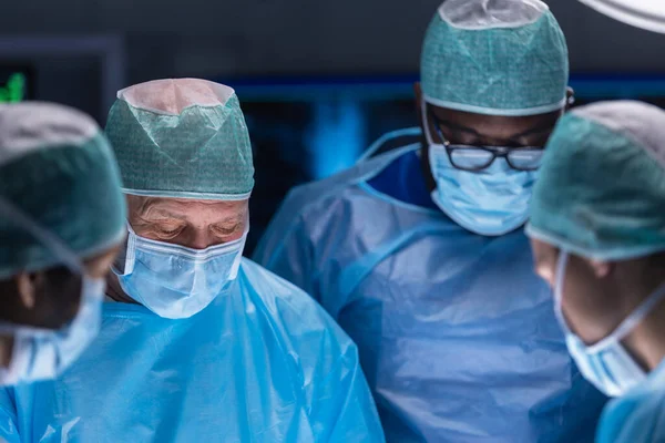 El equipo multirracial de cirujanos médicos profesionales realiza la operación quirúrgica en un hospital moderno. Los médicos están trabajando para salvar al paciente. Medicina, salud, cardiología y trasplante. — Foto de Stock