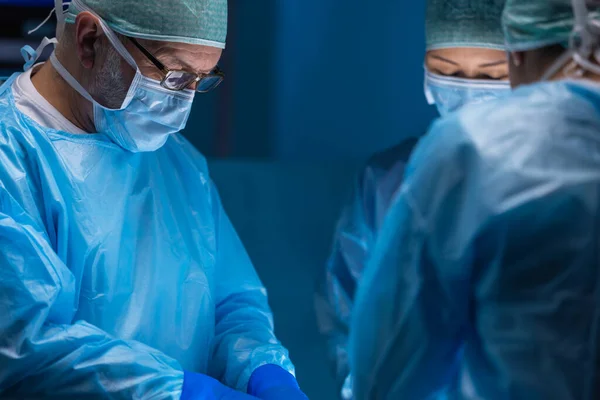 Multiracial team av professionella medicinska kirurger utför den kirurgiska operationen på ett modernt sjukhus. Läkarna arbetar för att rädda patienten. Medicin, hälsa, kardiologi och transplantation. — Stockfoto