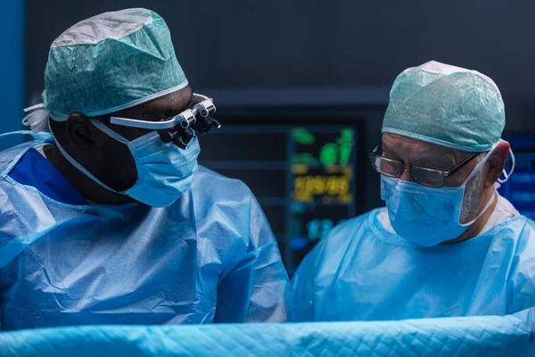 El equipo multirracial de cirujanos médicos profesionales realiza la operación quirúrgica en un hospital moderno. Los médicos están trabajando para salvar al paciente. Medicina, salud y neurocirugía. —  Fotos de Stock