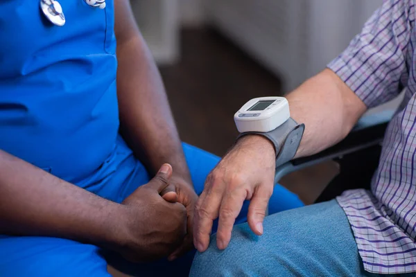 Cuidador está medindo a pressão arterial do velho deficiente. Enfermeira profissional e paciente em um lar de idosos. Assistência, reabilitação e saúde. — Fotografia de Stock