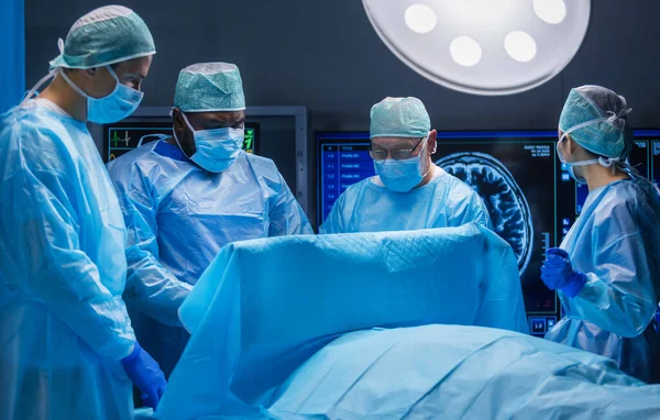 Professzionális orvosi sebészek multiracionális csapata végzi a műtétet egy modern kórházban. Az orvosok azon dolgoznak, hogy megmentsék a beteget. Gyógyászat, egészségügy és idegsebészet. — Stock Fotó