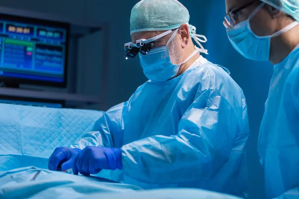 El equipo multirracial de cirujanos médicos profesionales realiza la operación quirúrgica en un hospital moderno. Los médicos están trabajando para salvar al paciente. Medicina, salud, cardiología y trasplante. — Foto de Stock