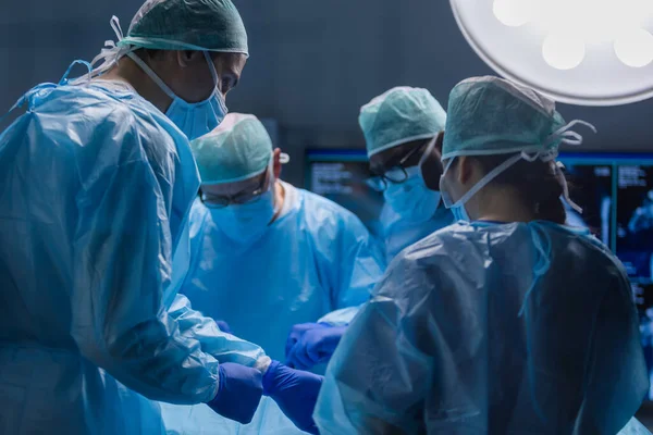 Багаторасова команда професійних медичних хірургів проводить хірургічну операцію в сучасній лікарні. Лікарі працюють, щоб врятувати пацієнта. Медицина, здоров'я, кардіологія та трансплантація . — стокове фото
