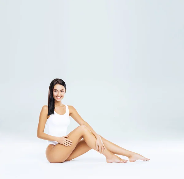 Aantrekkelijk en slank brunette meisje in wit ondergoed poseren in de studio. Gezond levensstijl, sport en lichaamsverzorging concept. — Stockfoto