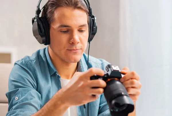 Lugar de trabajo de fotógrafos independientes. Un joven con una cámara está sentado en una mesa y mirando fotos. Concepto de trabajo remoto. — Foto de Stock