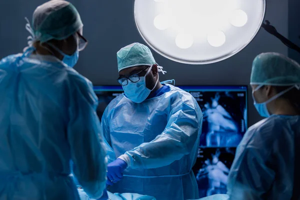 Многорасовая команда профессиональных медицинских хирургов проводит хирургическую операцию в современной больнице. Врачи работают, чтобы спасти пациента. Медицина, здоровье, кардиология и трансплантация. — стоковое фото