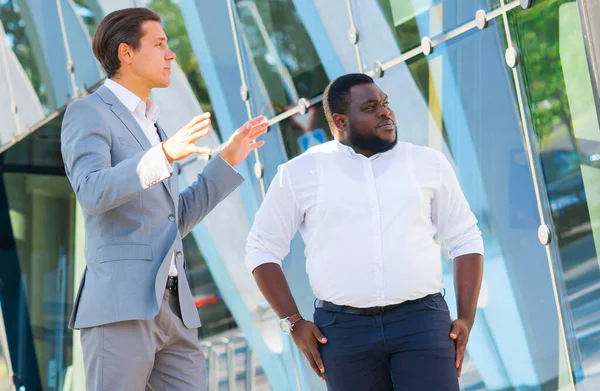 Concetto di finanza, affari e cooperazione. Due uomini d'affari di successo stanno parlando per strada. Gli impiegati discutono di affari all'aperto. — Foto Stock