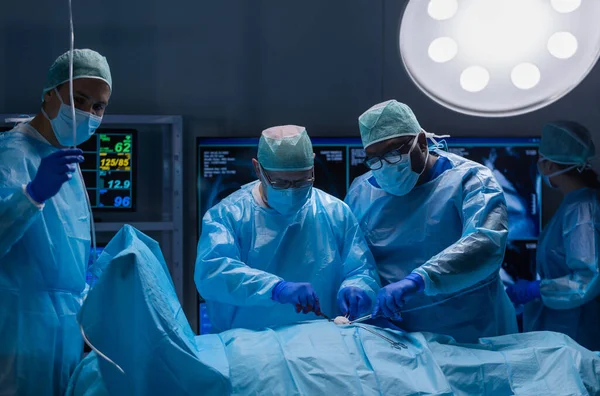 Багаторасова команда професійних медичних хірургів проводить хірургічну операцію в сучасній лікарні. Лікарі працюють, щоб врятувати пацієнта. Медицина, здоров'я, кардіологія та трансплантація . — стокове фото