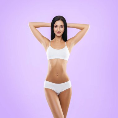 Stüdyoda poz veren beyaz mayo giymiş genç, fit ve güzel esmer kadın. Zindelik, diyet ve cilt bakımı kavramı.