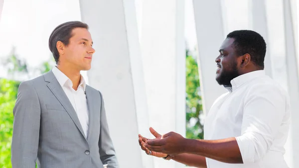 Finance, business and cooperation concept. Two successful businessmen are talking on the street. Office workers are discussing business issues outdoor. — Stock Photo, Image