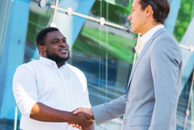 Finans, iş ve işbirliği konsepti. İki başarılı iş adamı sokakta konuşuyor. Ofis çalışanları iş meselelerini dışarıda tartışıyorlar..