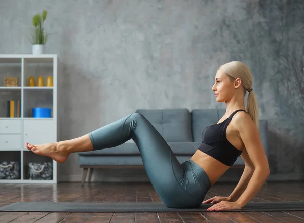 Mulher loira esbelta jovem em sportswear envolve-se na aptidão em casa. Conceito de desporto, saúde e estilo de vida. — Fotografia de Stock