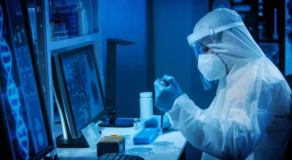 Επιστήμονας εργάζεται σε ένα σύγχρονο επιστημονικό εργαστήριο χρησιμοποιώντας εργαστηριακό εξοπλισμό, μικροσκόπιο και τεχνολογία υπολογιστών. Εφεύρεση νέων εμβολίων. Έννοια της επιστήμης και της υγείας. Εικόνα Αρχείου