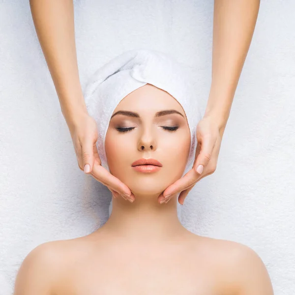 Une jeune femme en bonne santé reçoit des massages pour le visage, la peau et le cou dans le salon de spa. Concept santé, bien-être et rajeunissement. — Photo