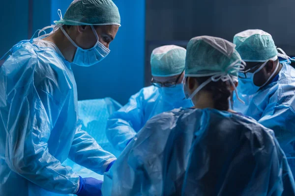 Πολυφυλετική ομάδα επαγγελματιών ιατρών χειρουργών εκτελεί τη χειρουργική επέμβαση σε ένα σύγχρονο νοσοκομείο. Οι γιατροί προσπαθούν να σώσουν τον ασθενή. Ιατρική, υγεία, καρδιολογία και μεταμόσχευση. — Φωτογραφία Αρχείου