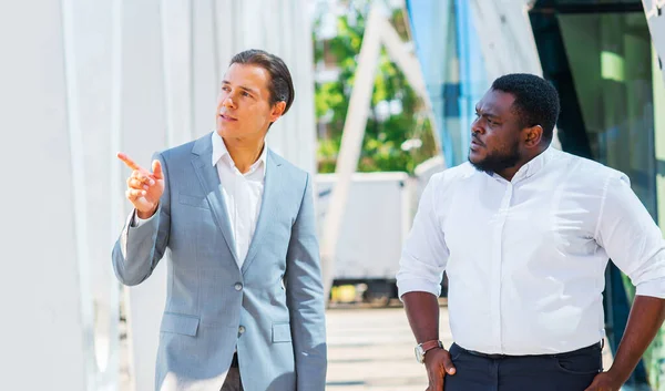 Finance, business and cooperation concept. Two successful businessmen are talking on the street. Office workers are discussing business issues outdoor. Stock Photo