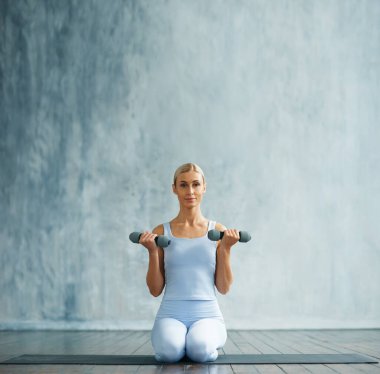 Spor giyimli genç, narin sarışın kadın geniş bir eğitim odasında fitness yapıyor. Spor, sağlık, jimnastik ve yaşam tarzı konsepti.