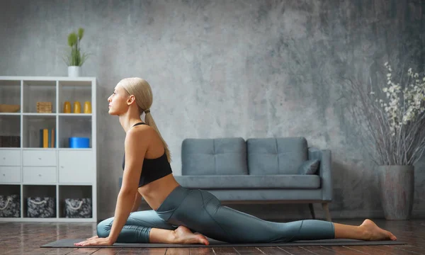 Joven mujer rubia delgada en ropa deportiva se dedica a la aptitud en casa. Concepto de deporte, salud y estilo de vida. — Foto de Stock