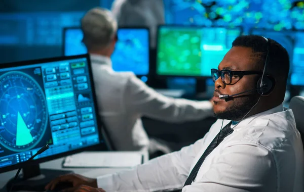 El oficial de control de vuelo de la aeronave monitorea la aproximación de la aeronave desde la torre de control. La oficina de servicios aéreos está equipada con sistemas de navegación, radares y estaciones informáticas. Concepto de aviación. — Foto de Stock