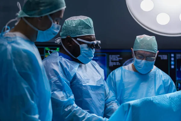 El equipo multirracial de cirujanos médicos profesionales realiza la operación quirúrgica en un hospital moderno. Los médicos están trabajando para salvar al paciente. Medicina, salud y neurocirugía. — Foto de Stock