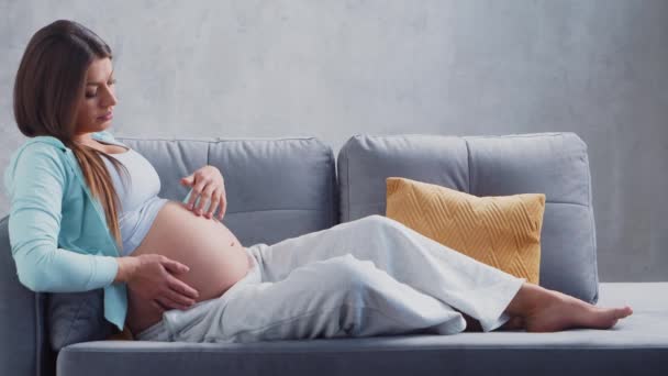 La giovane donna incinta sta riposando a casa e aspetta un bambino. Il concetto di gravidanza, maternità, salute e stile di vita. — Video Stock