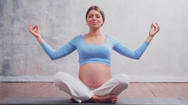 Молода вагітна жінка займається вправами йоги і медитує вдома. Концепція здоров'я, уважності, релаксації та оздоровлення . — стокове відео