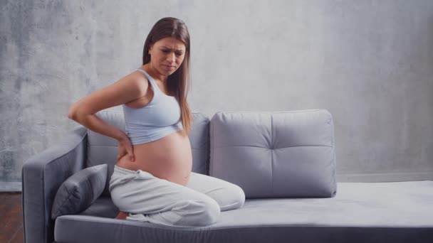Молодая беременная женщина страдает от болей в спине. Концепция беременности, материнства, здоровья и образа жизни. — стоковое видео