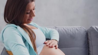 Genç hamile kadın evde dinleniyor ve bebek bekliyor. Hamilelik, annelik, sağlık ve yaşam tarzı kavramı.