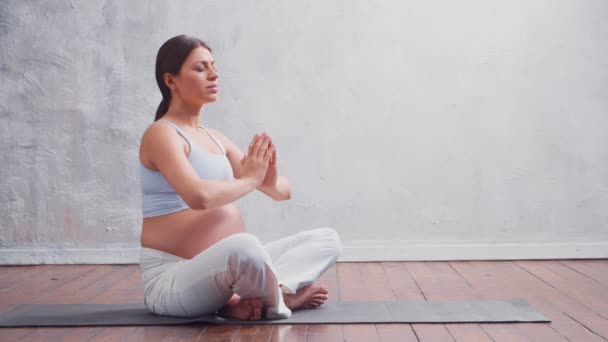 Jeune femme enceinte faisant des exercices de yoga et méditant à la maison. Le concept de santé, de pleine conscience, de relaxation et de bien-être. — Video